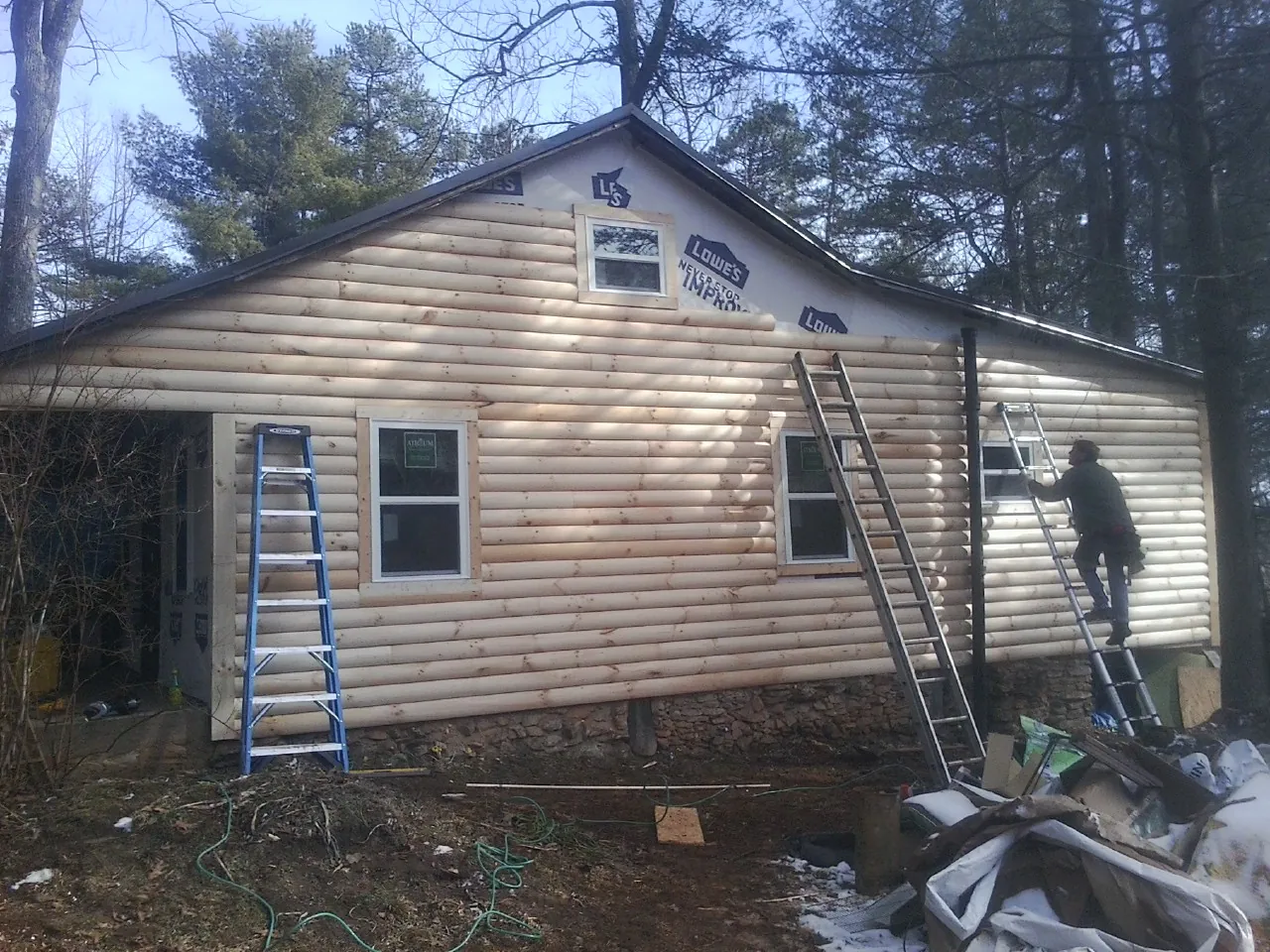 Ladders set against fresh log siding during an exterior remodel in Saint Ann