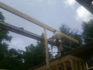 Carpenter setting a ridge beam over a new addition frame — Ice Dam Removal by Roofing Brothers in Saint Ann