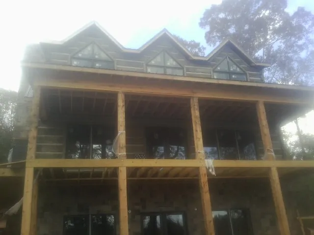 Dormers and porch framing on a large log home under construction — Roof Coating work by our crew in Saint Ann