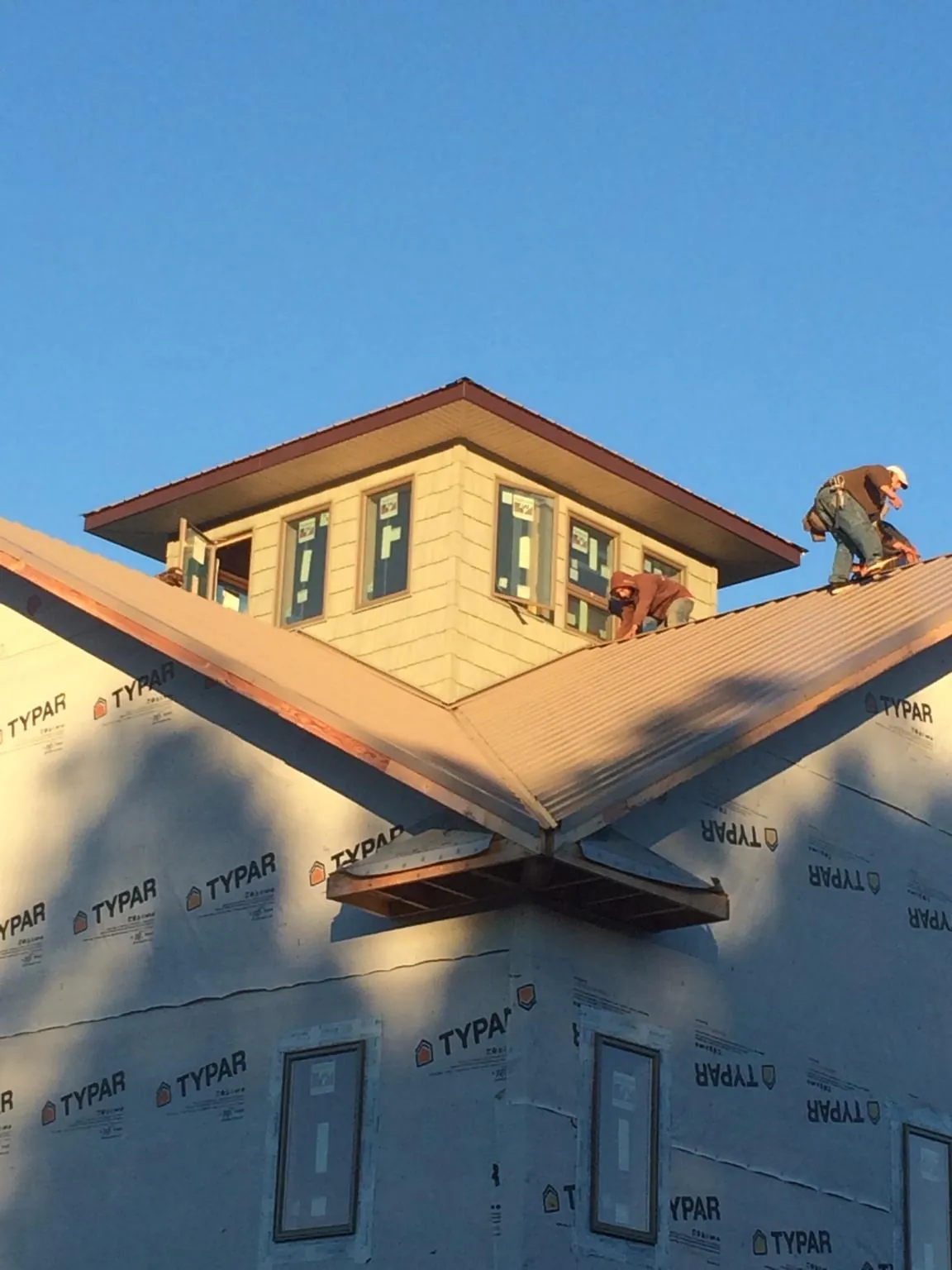 Roofers working around a rooftop cupola on a new metal roof at sunset — Roof Waterproofing in Saint Ann by Roofing Brothers